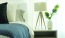 a bed with a lamp and a vase with flowers on it