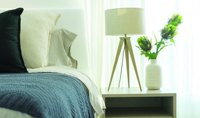 a bed with a lamp and a vase with flowers on it